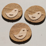 Laser-cut and engraved birds on maple in the sun